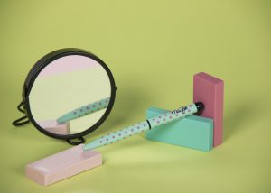 Bolígrafo topos color turquesa claro reflejado en un espejo redondo