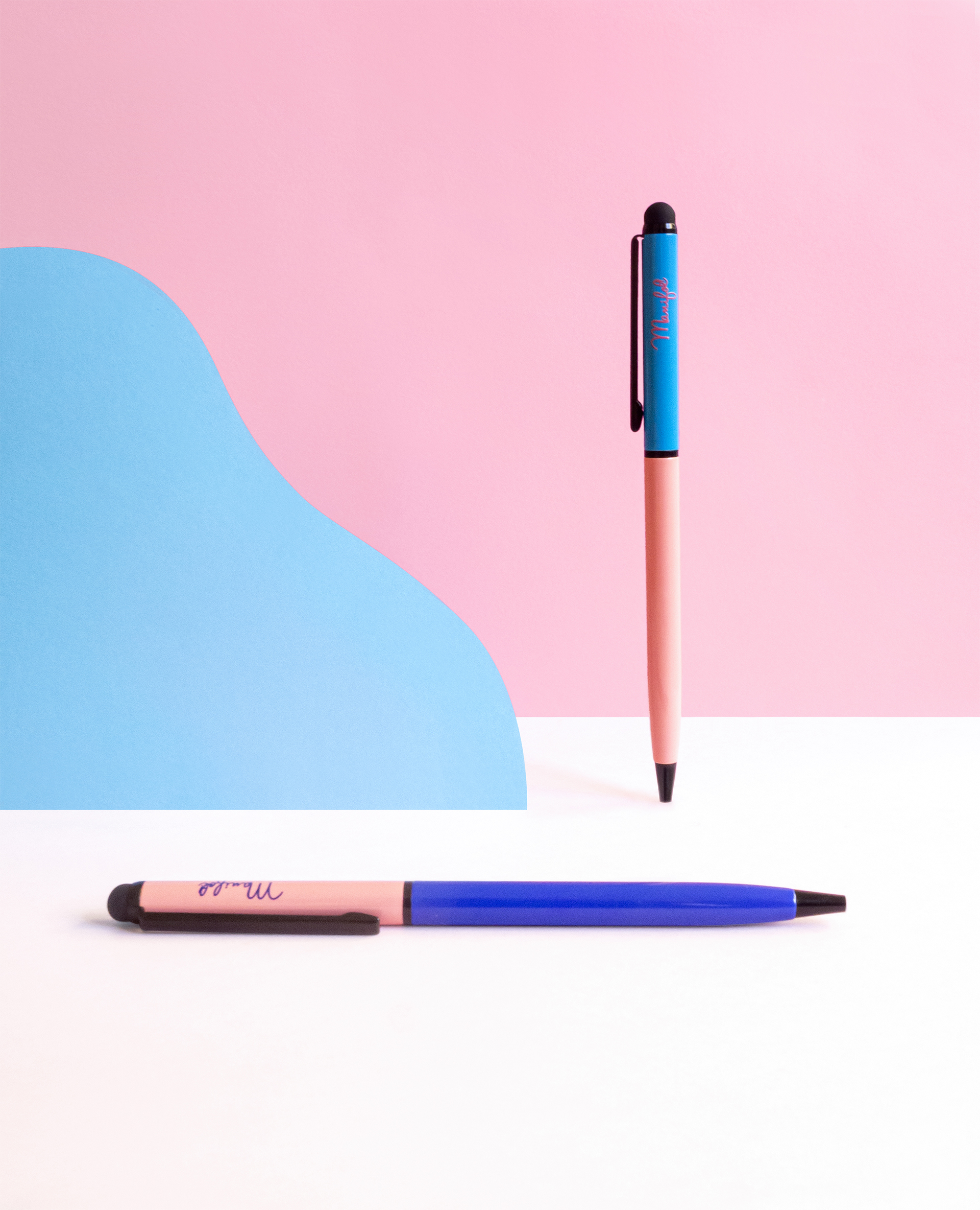 Dos bolígrafos de varios colores sobre fondo de cartulinas de colores
